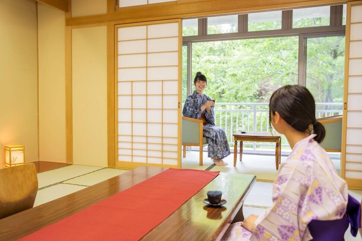 A traditional Japanese room with tatami flooring, a low table, and a sliding door.