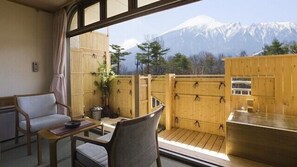 A balcony with a view of snow-capped mountains, wooden furniture, and a small table.