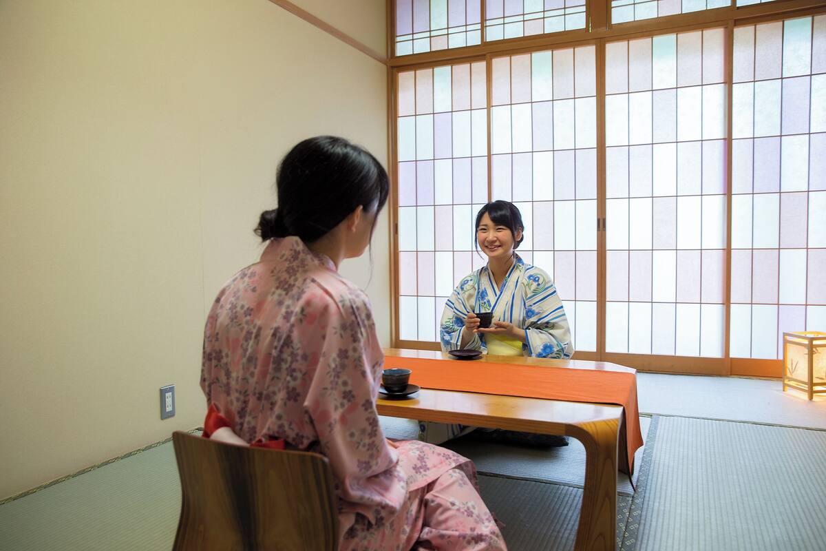 A traditional Japanese room with tatami flooring, a low wooden table, and a sliding door with shoji screens.