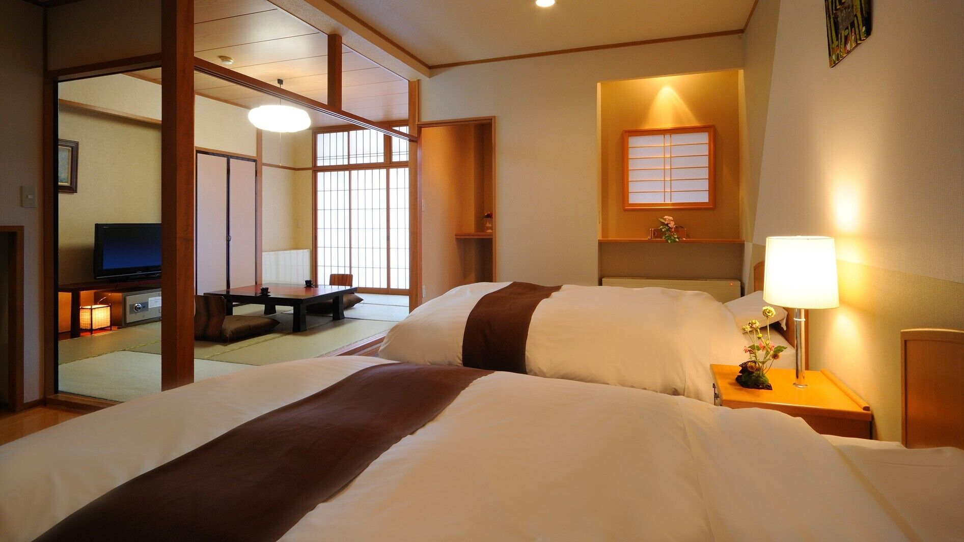 A hotel room with a bed, a TV, a desk, and a window with a view.