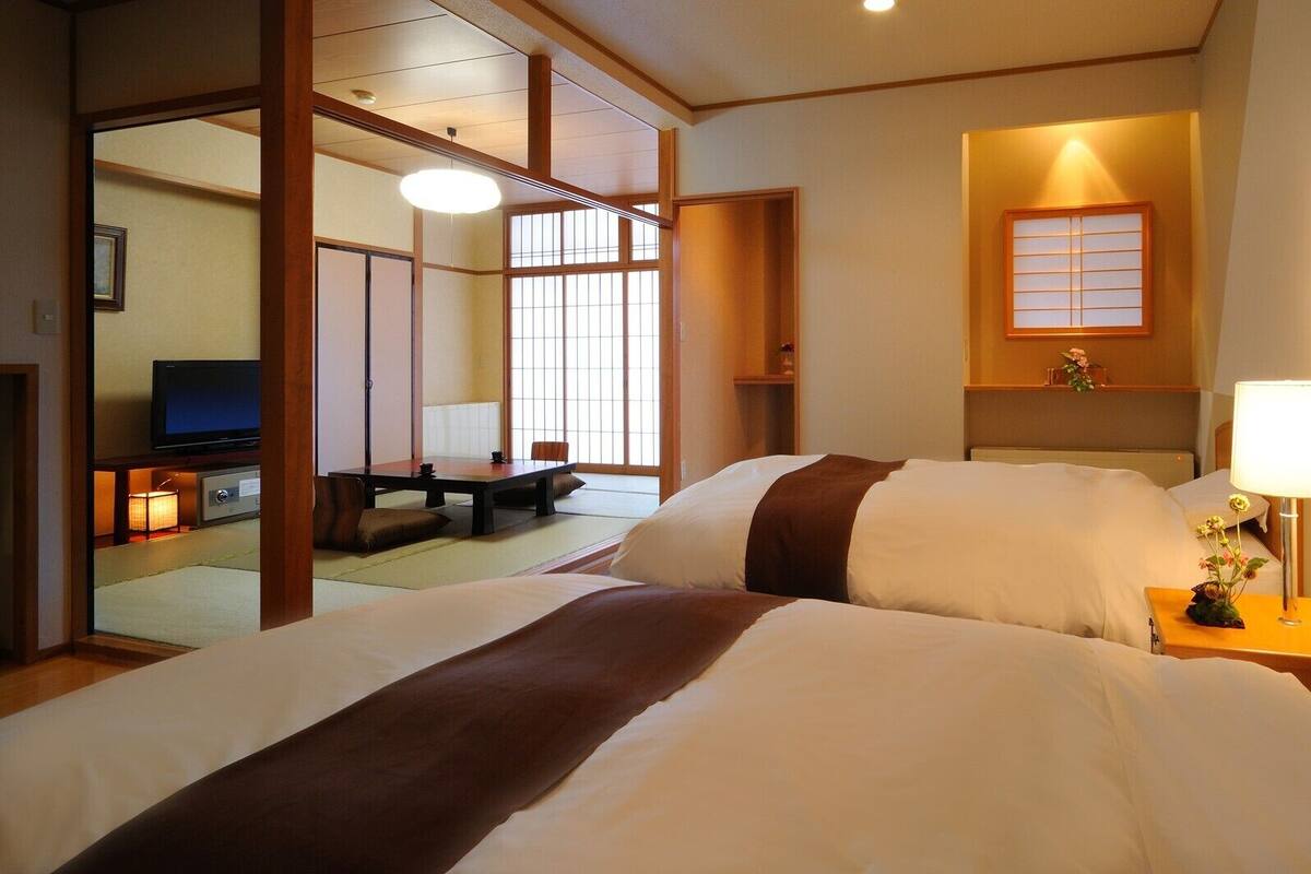 A hotel room with a bed, a TV, a desk, and a window with a view.