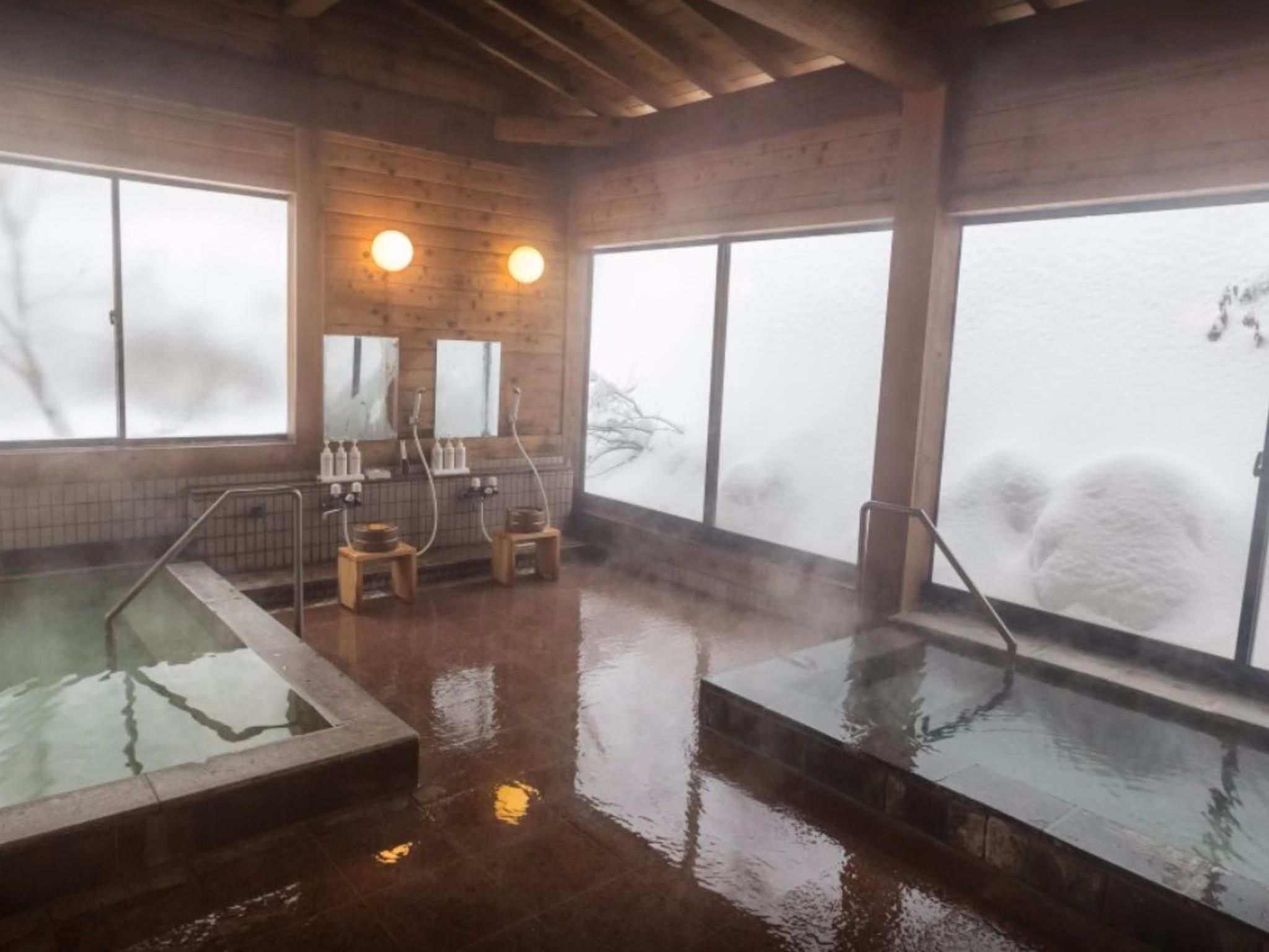 Un baño de vapor con paredes de madera, ventanas grandes y dos jacuzzis.
