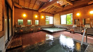 A wooden spa with a hot tub, wooden benches, and a tiled floor. - Nisshinkan (Kusatsu)