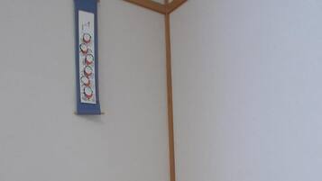 A corner of a room with a white table, a small green plant, and a hanging wall decoration.