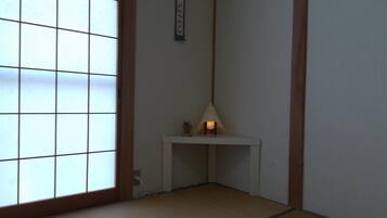 Ein traditioneller japanischer Raum mit Tatami-Bodenbelag, Shoji-Schirm, einem kleinen Tisch mit Lampe und einer Wandrolle.