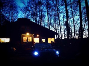 A house with a car parked in front, surrounded by trees.