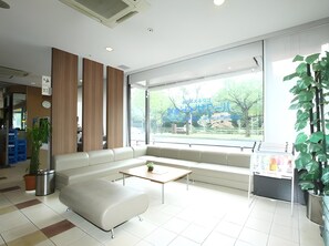 Un área de espera moderna con un sofá, una mesa de centro y un amplio ventanal con vistas al exterior.