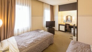 Ein Hotelzimmer mit zwei Betten, einem Schreibtisch mit Stuhl, einem Fernseher und einem Badezimmer mit Spiegel.
