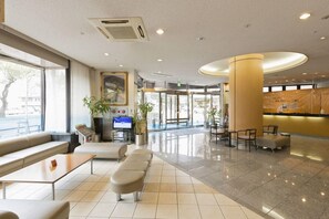 En hotellobby med sittgrupper, en receptionsdisk och en tv-skärm.
