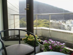 A balcony with a chair and potted plants, overlooking a cityscape with buildings and greenery. - Business Hotel Park Side Takamatsu (Takamatsu)