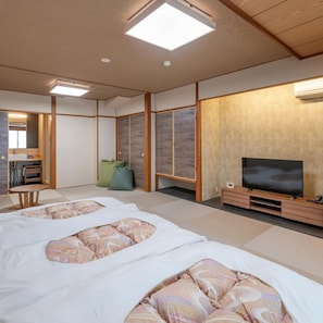 A traditional Japanese-style room with tatami flooring, a television, and a sliding door. - Subaruyado Yoshino (Tokushima)