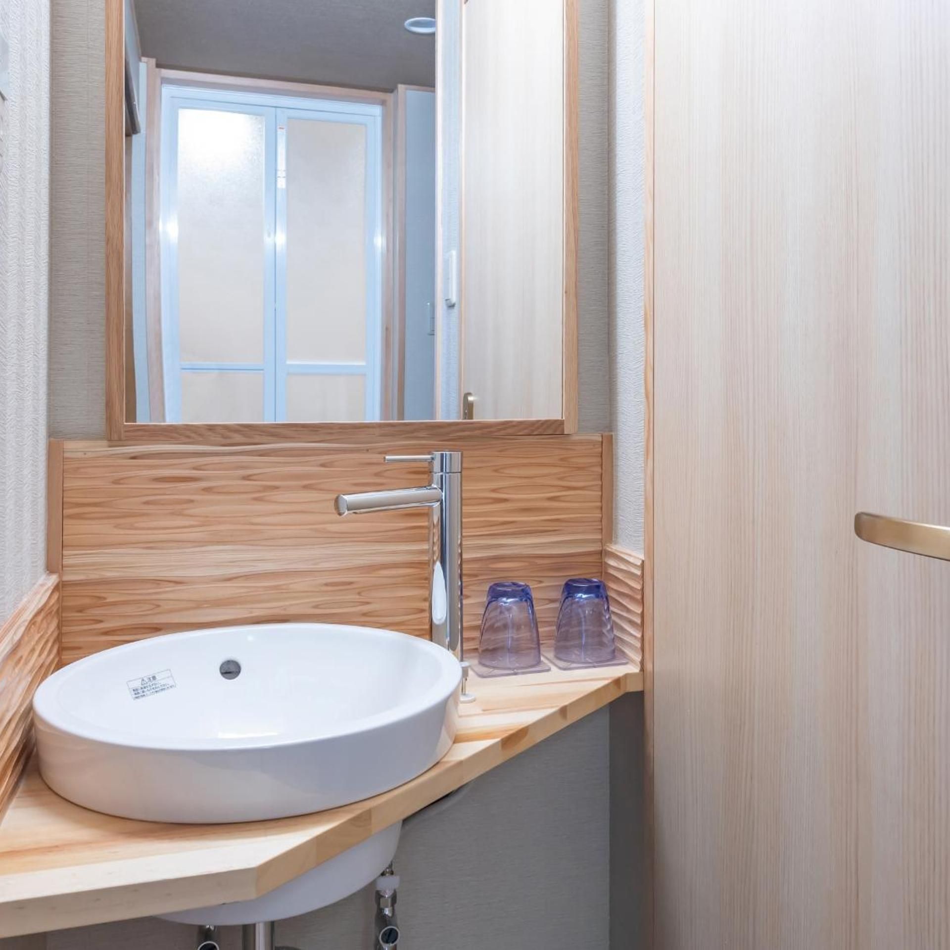 A bathroom with a white sink, a mirror, and a wooden vanity.