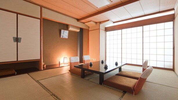 A traditional Japanese room with tatami flooring, a low table, cushions, sliding doors, and a large window. - Subaruyado Yoshino (Tokushima)