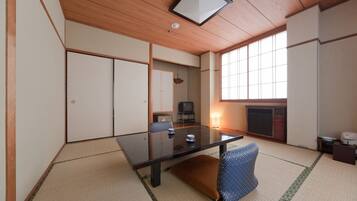 A traditional Japanese-style room with tatami flooring, a low table, and a television.