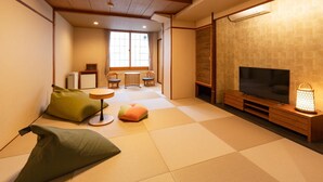A traditional Japanese-style living room with tatami flooring, a television, a small table, and a sofa. - Subaruyado Yoshino (Tokushima)