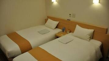A hotel room with two single beds, each with a headboard, bedside tables, and a nightstand.