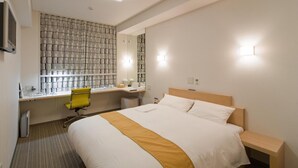 Een hotelkamer met een bed, een bureau, een stoel, een spiegel en een douche.