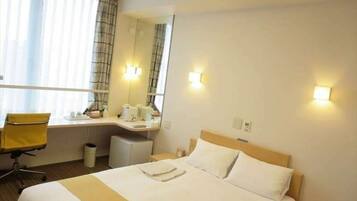 Ein Hotelzimmer mit einem Bett, einem Schreibtisch, einem Sessel und einem Fenster mit Vorhängen.