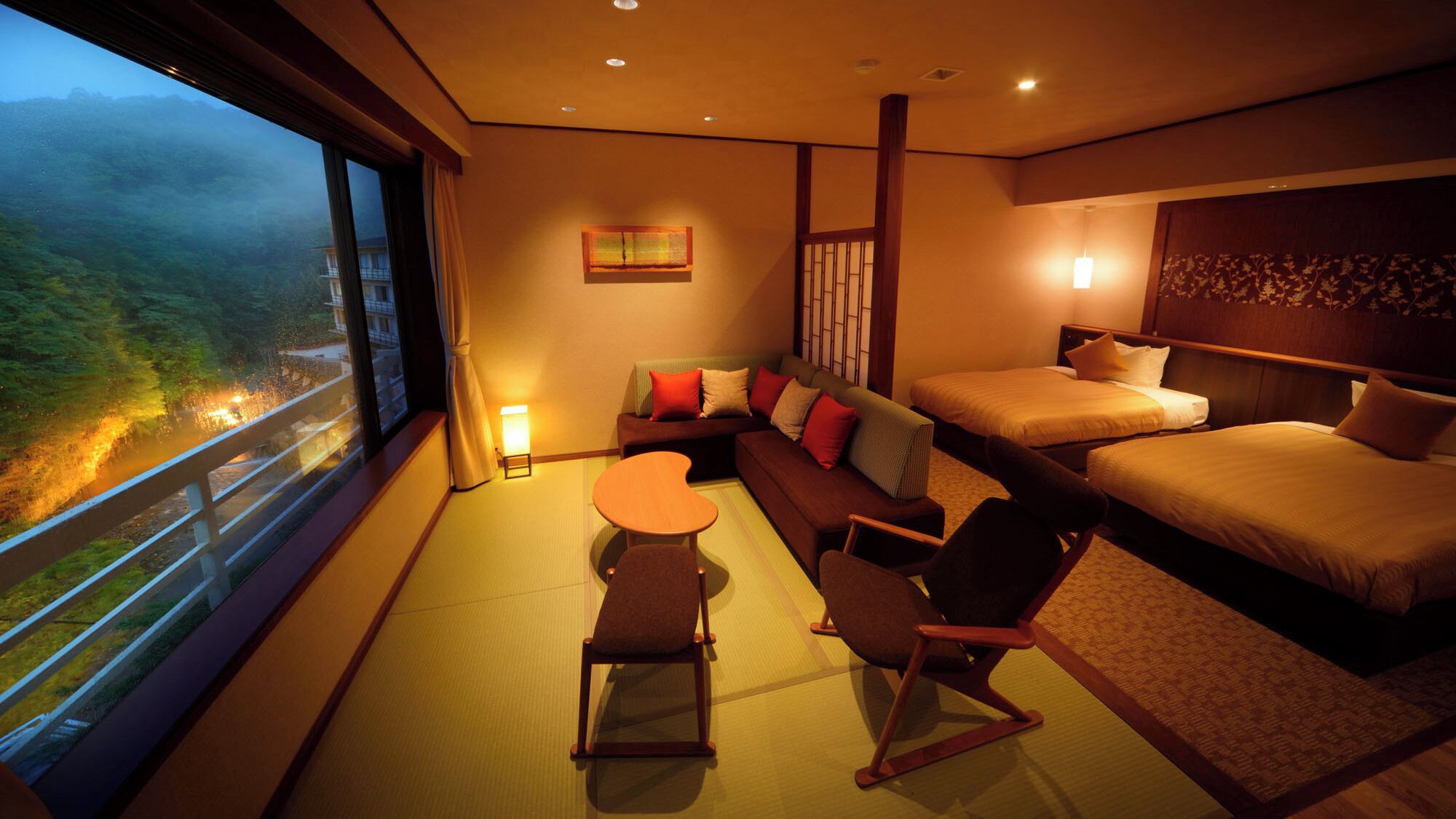 Een hotelkamer met een bank, twee bedden, een tafeltje en stoelen.