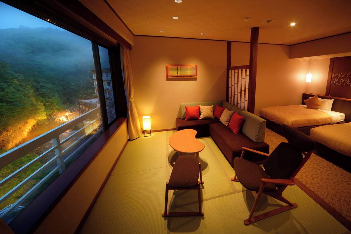 Ett hotellrum med en soffa, två sängar, ett litet bord och stolar.