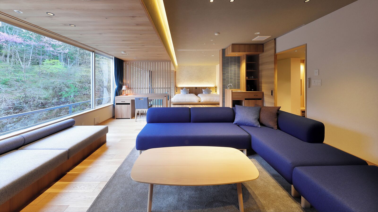 Un intérieur moderne avec un grand canapé, une petite table et une vue dégagée grâce à de grandes fenêtres.