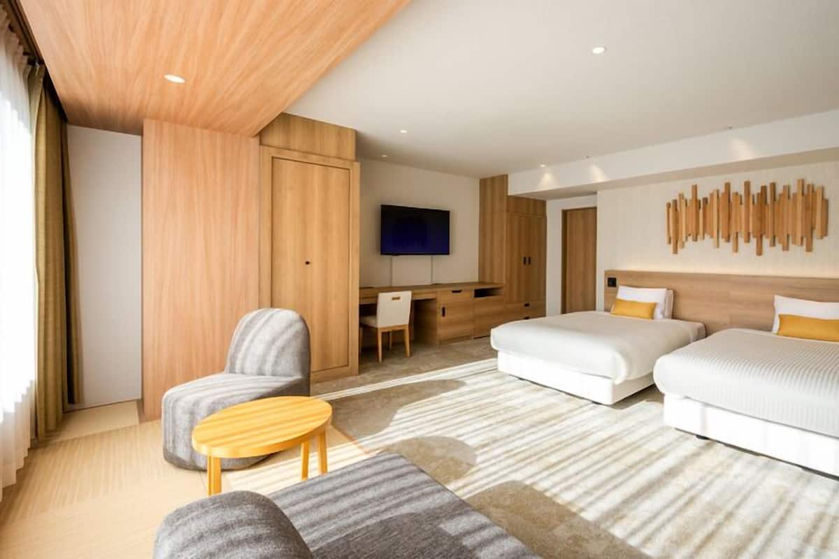 Ett modernt hotellrum med en säng, ett skrivbord, en stol och en TV.