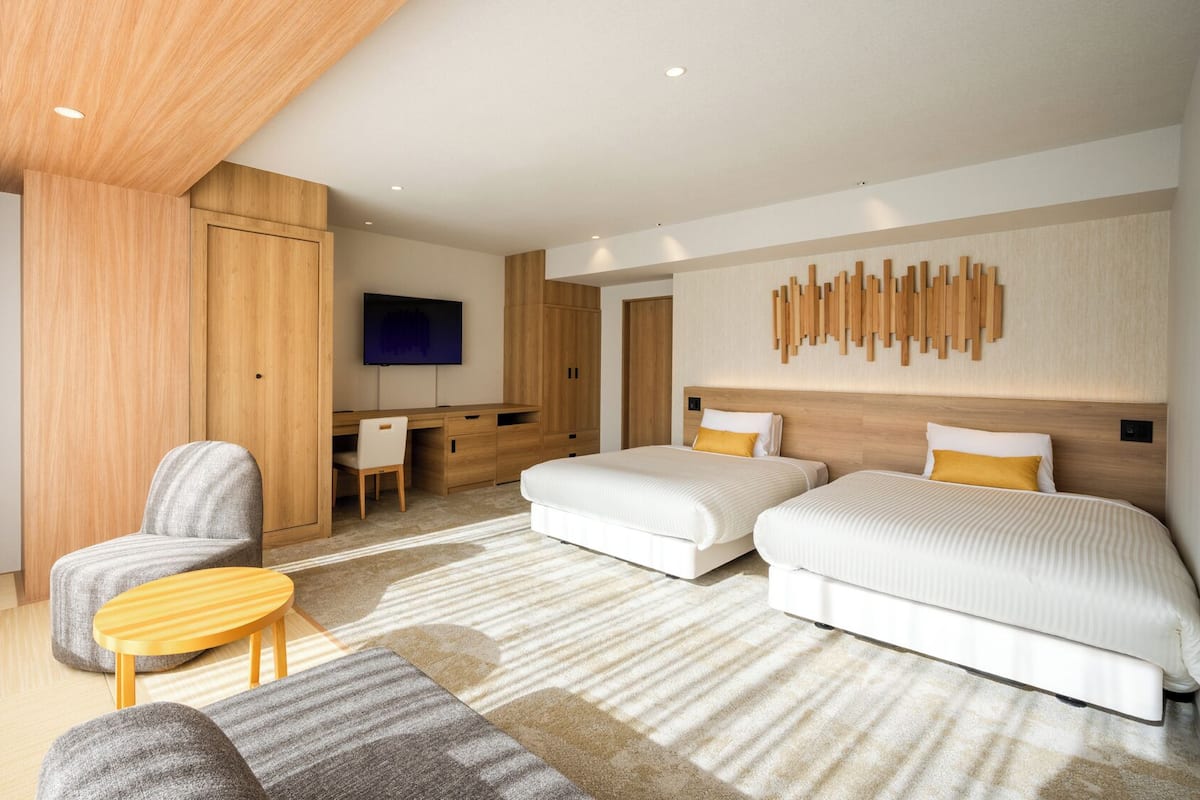 Ett modernt hotellrum med en säng, två sängbord, ett skrivbord, en stol och en TV.
