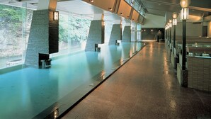 A spacious indoor area with a long, reflective pool, stone pillars, and a high ceiling with skylights. - Yu No Mori Hotel Shidotaira (Hanamaki)