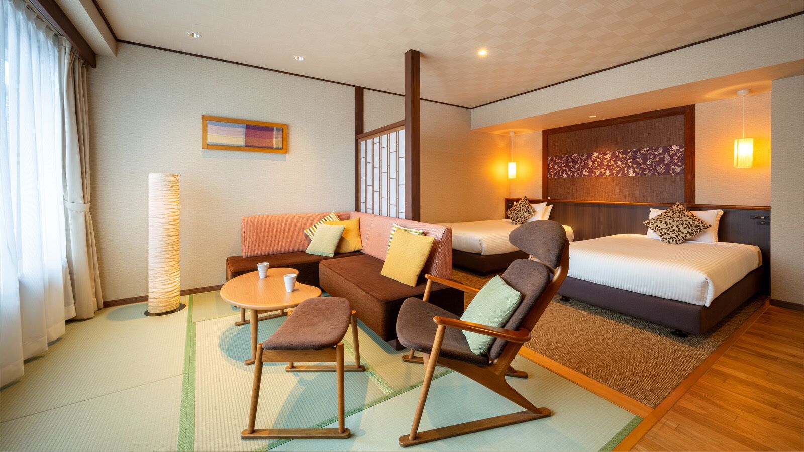 Een hotelkamer met een bank, stoelen, een kleine tafel, een bed en een groot raam.