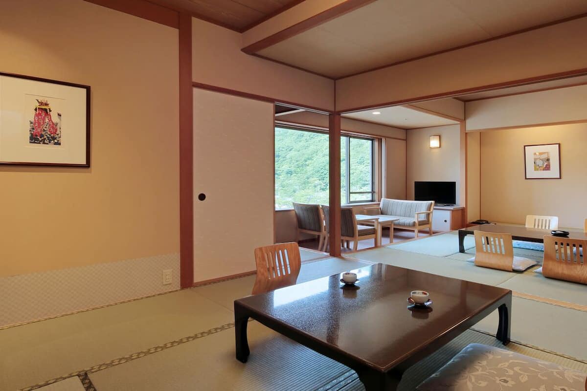 Ett traditionellt japanskt rum med tatamimattor på golvet, ett lågt bord och en tv i bakgrunden.