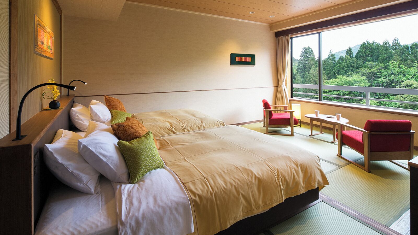 Een hotelkamer met een groot bed, een klein tafeltje, twee stoelen en uitzicht op groen door het raam.