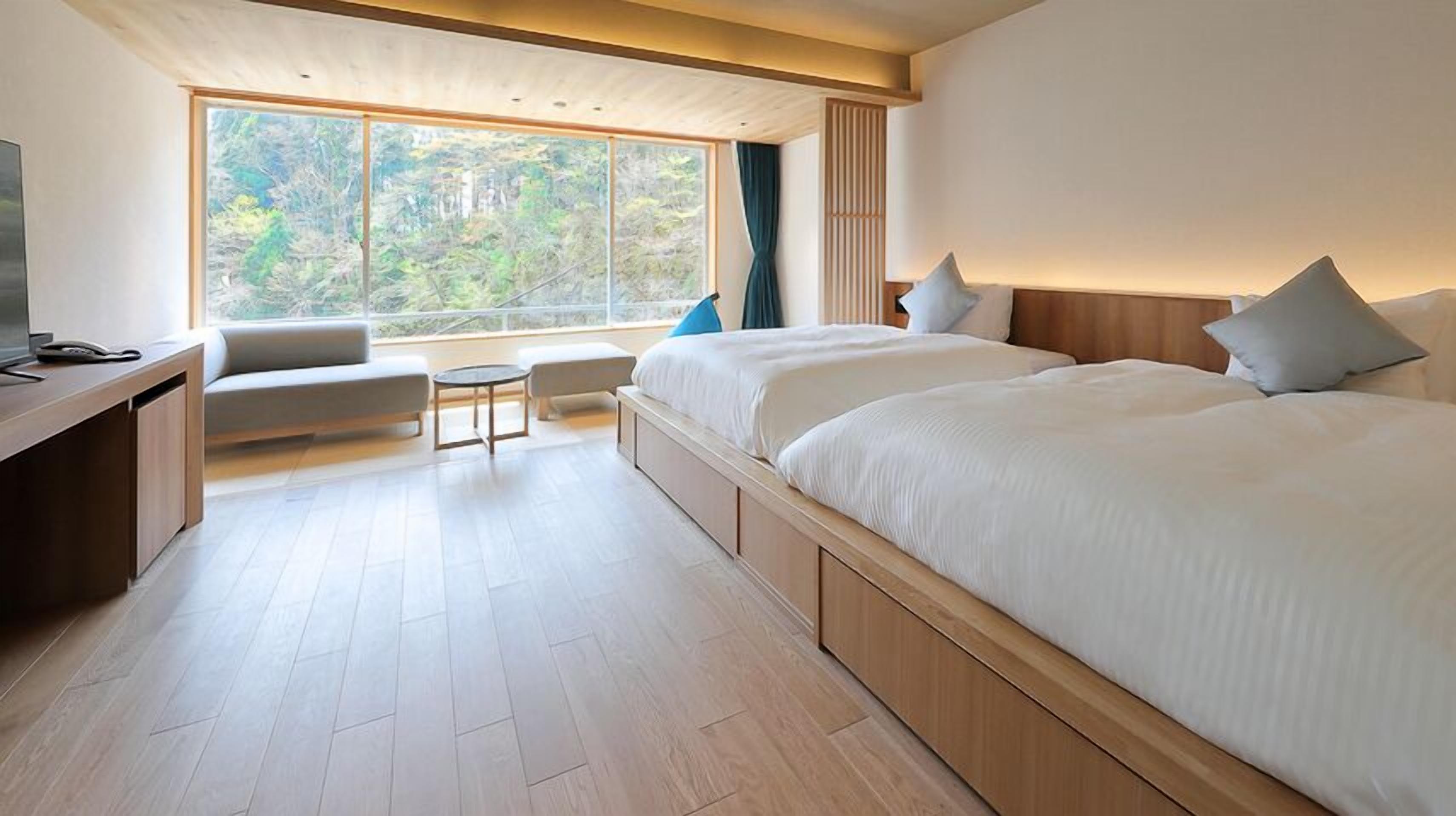 Een moderne hotelkamer met een groot bed, een bureau, een stoel en uitzicht op de omgeving.