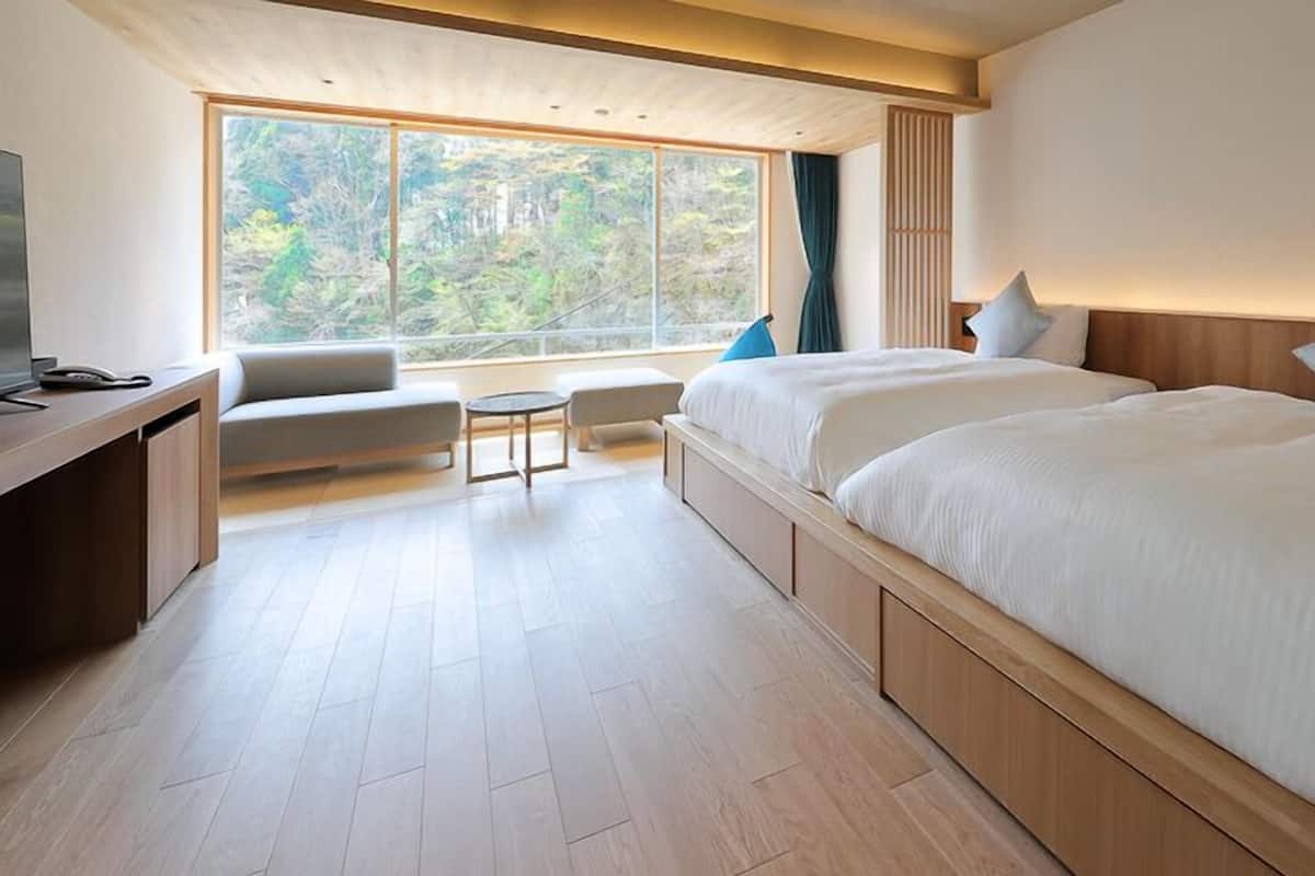 Ett modernt hotellrum med en stor säng, ett skrivbord, en stol och utsikt över omgivningarna.