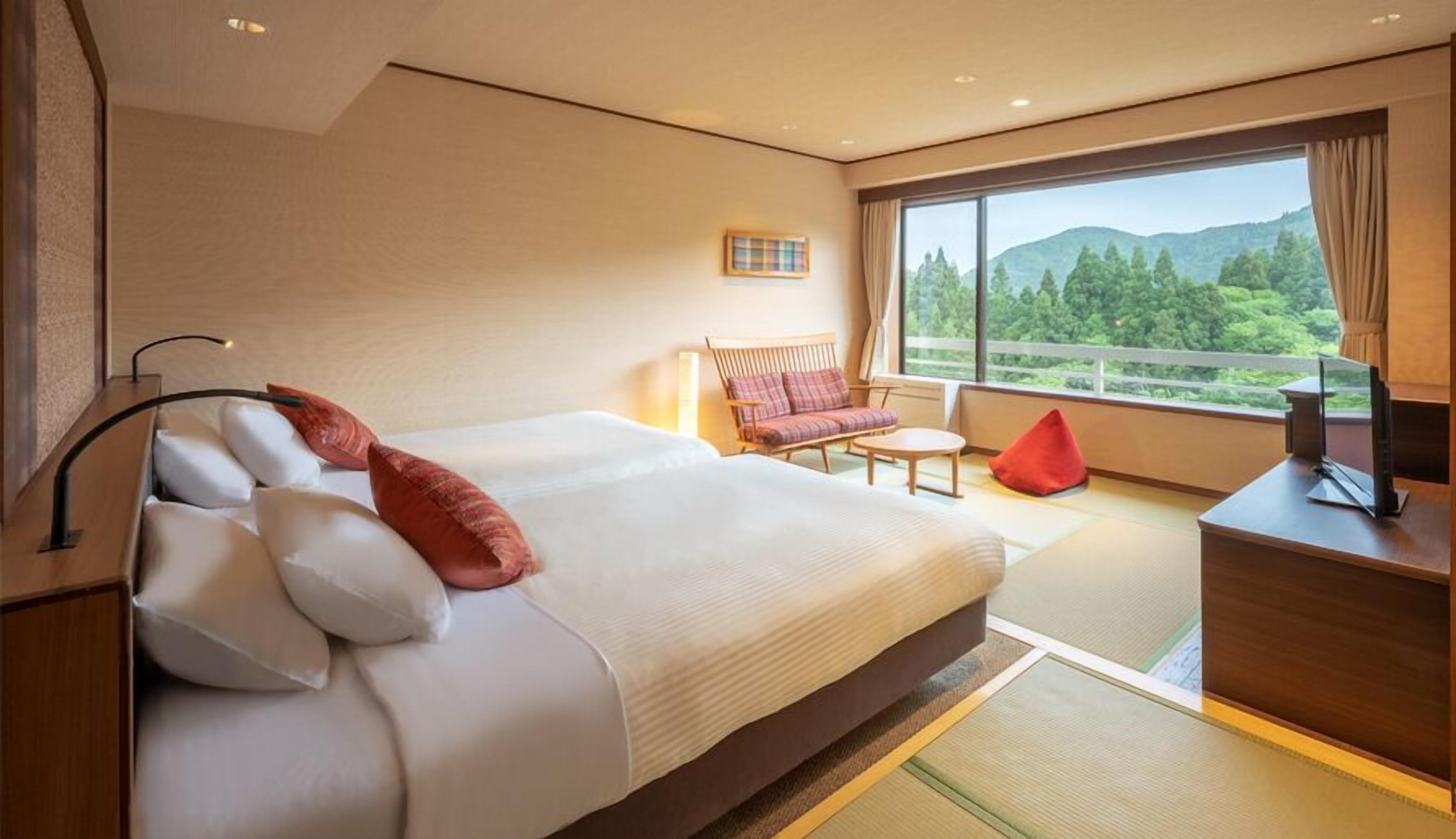 Een hotelkamer met een groot bed, een bank, een bureau en uitzicht op het landschap.