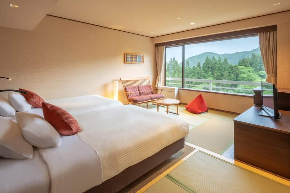 Ett hotellrum med en stor säng, en soffa, ett skrivbord och utsikt över omgivningarna.
