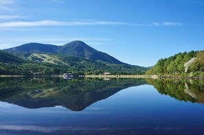 Un lago tranquilo con una montaña al fondo y un cielo despejado.
