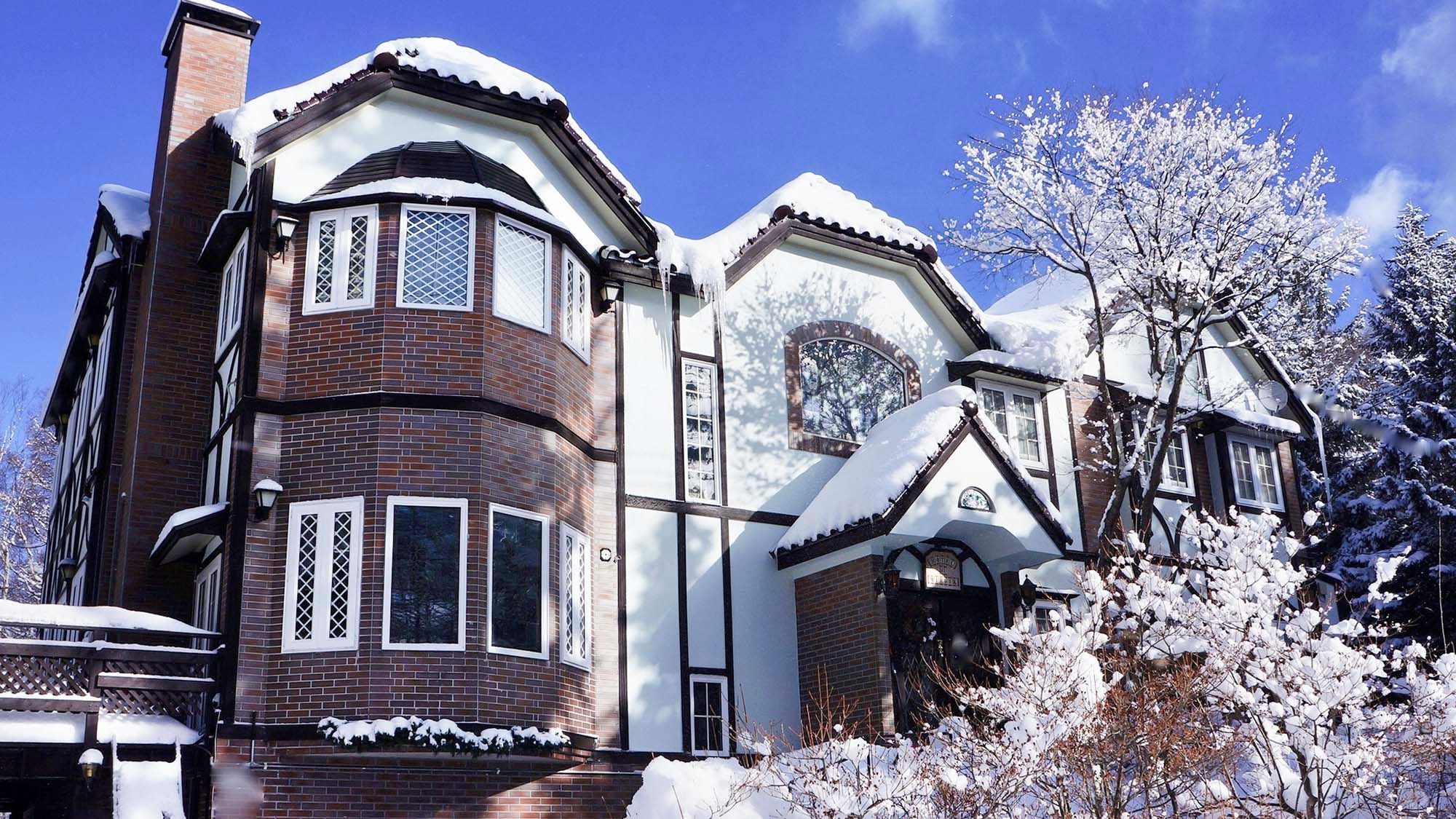 Una casa de estilo victoriano con ventanal saliente, fachada de ladrillo y exterior cubierto de nieve.