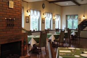 A dining area with brick walls, green tablecloths, and wooden chairs.