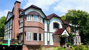 En stor byggnad med flera våningar, ett framträdande hörntorn, stora fönster och en traditionell arkitektonisk stil.