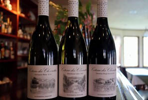 Tres botellas de vino con etiquetas, sobre una barra.