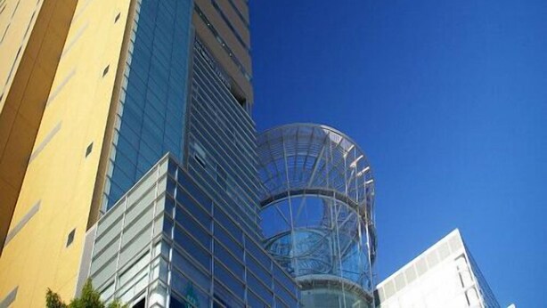 Un immeuble de grande hauteur doté d’une façade moderne en verre et d’une structure cylindrique en verre à sa base.