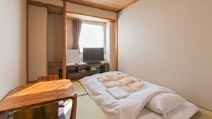 Une chambre d’hôtel avec un lit, un bureau, une télévision et une fenêtre avec des rideaux.