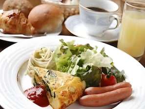 Een bord met een salade, een plakje quiche, worstjes en ketchup.