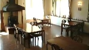 A spacious dining area with a high ceiling, large windows, and a central table surrounded by chairs. - Guest House Hilltop (Nagano)
