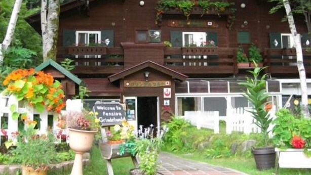 A rustic wooden building with a sign reading 'Welcome to Pension Grindelwald.' - Pension Grindelwald (Matsumoto)