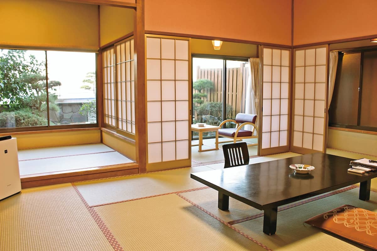 Une pièce de style japonais traditionnel, avec un sol recouvert de tatamis, une table basse et des portes coulissantes.