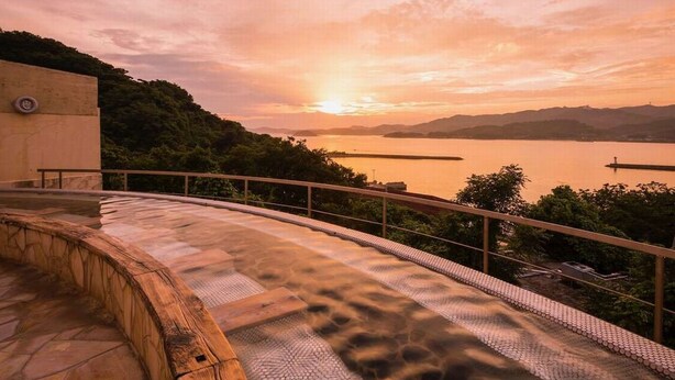 A curved stone pathway leading to a scenic overlook with a sunset view over a body of water. - Wano Resort Hazu (Gamagori)
