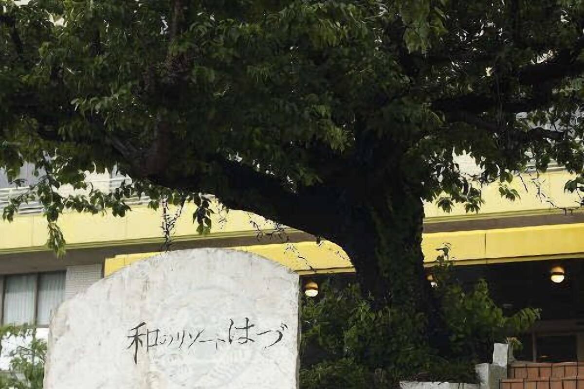 Ein Steinsockel mit japanischen Schriftzeichen, eine Backstieppe und ein Baum.