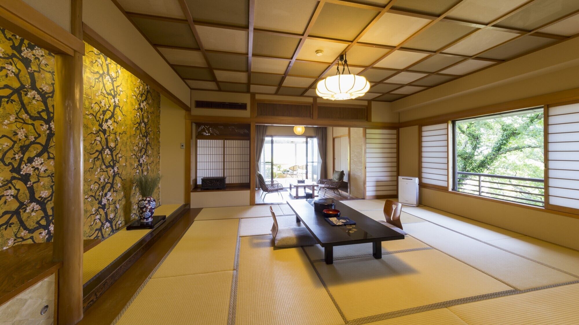 Een traditionele Japanse kamer met tatami vloerbedekking, een lage tafel, stoelen en uitzicht door een shoji scherm.
