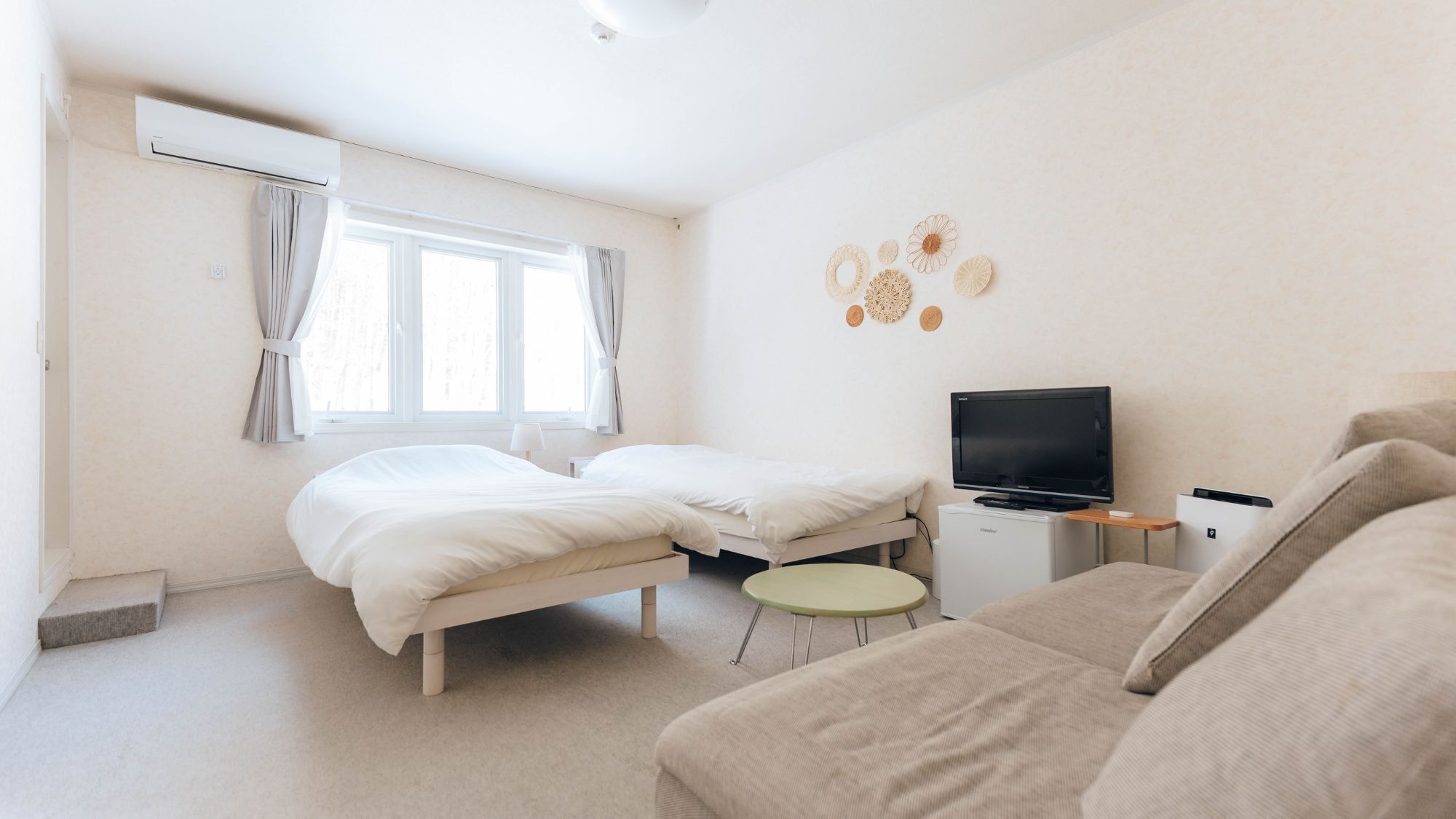 A bedroom with a bed, a TV, a small table, and a sofa.